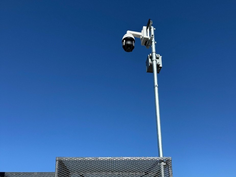 Pole-mounted CCTV camera installed above a secured cell-site equipment compound